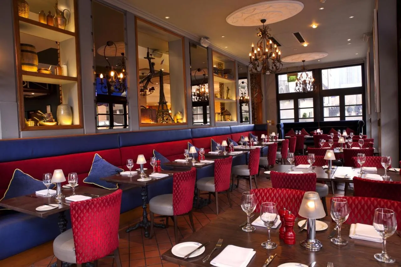 a dining room with tables and red chairs at Holiday Inn Glasgow City Theatreland by IHG in Glasgow