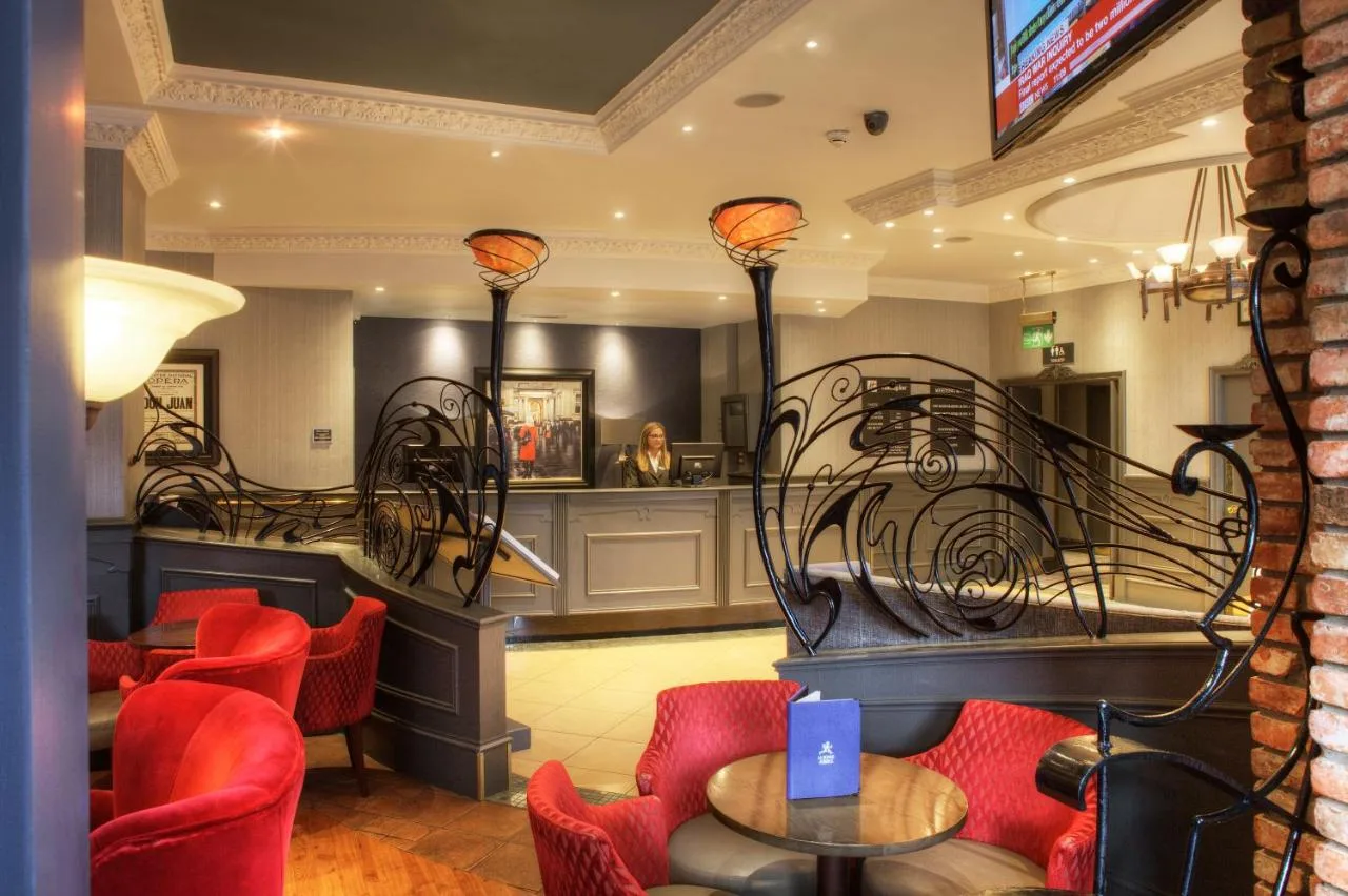 a restaurant with red chairs and a spiral staircase at Holiday Inn Glasgow City Theatreland by IHG in Glasgow